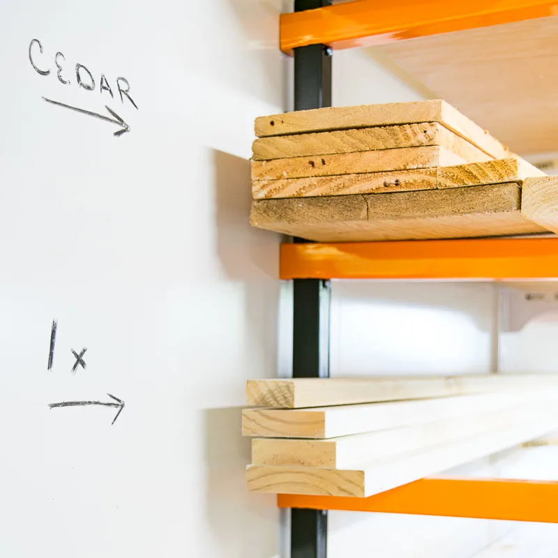 Regal mit zwei orangefarbenen Metallhalterungen, die Holzbretter halten, perfekt für Ihre Werkstatt oder kleine Garage. Das obere Regal trägt die Aufschrift „CEDAR“ und das untere Regal trägt die Aufschrift „1x“.